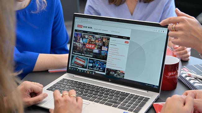Rund um einen Laptop sitzen arbeitende Personen, der Bildschirm zeigt die Webseite von der.ORF.at